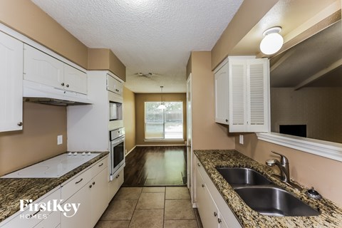 A kitchen with white cabinets and a granite countertop.