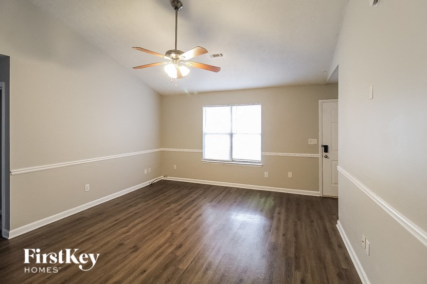 the spacious living room with hardwood flooring and a ceiling fan