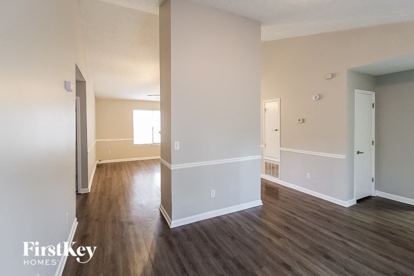 an empty living room with wood floors and white walls