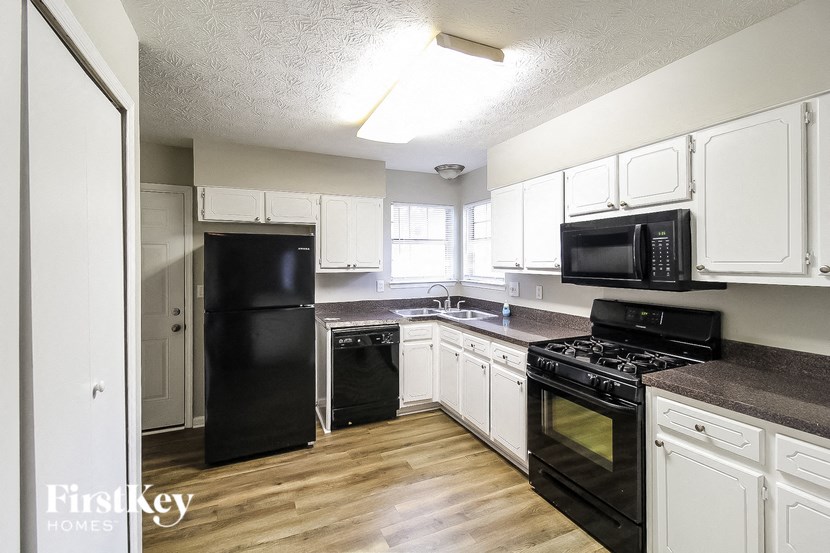 an empty kitchen with black appliances and white cabinets