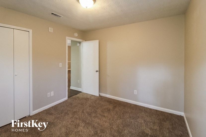 an empty living room with a brown carpet and a door to a closet