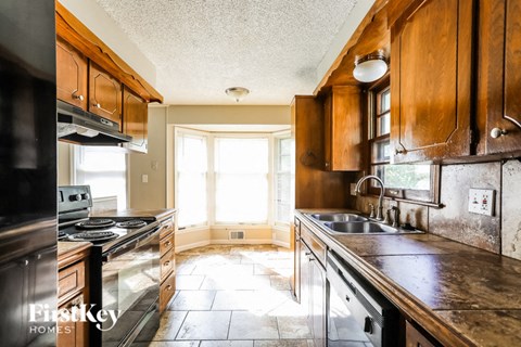 A kitchen with wooden cabinets and a stove top oven.