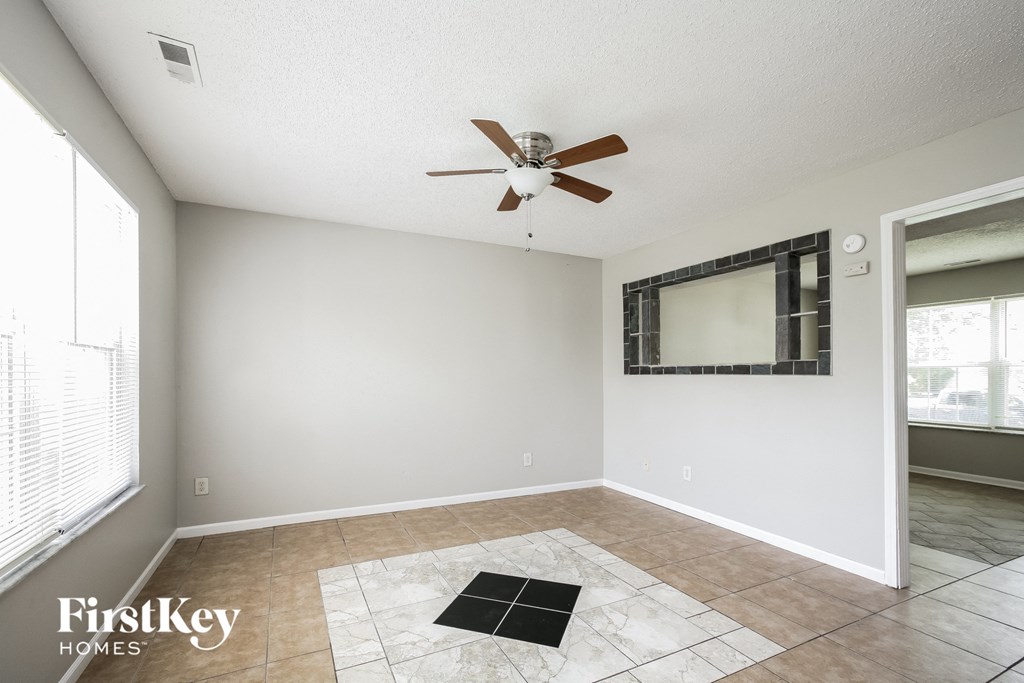 an empty living room with a ceiling fan and a window