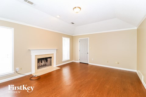 A spacious room with a fireplace and wooden floors.