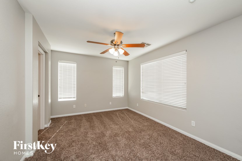 A room with a ceiling fan and carpeted floor.