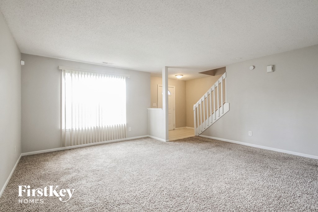 A spacious room with a staircase leading to another room.