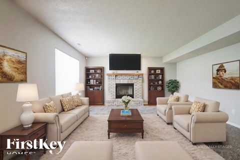 A living room with a fireplace and a tv on the wall.