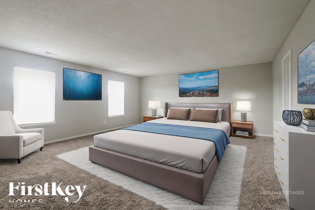 A bedroom with a large bed and two paintings on the wall.