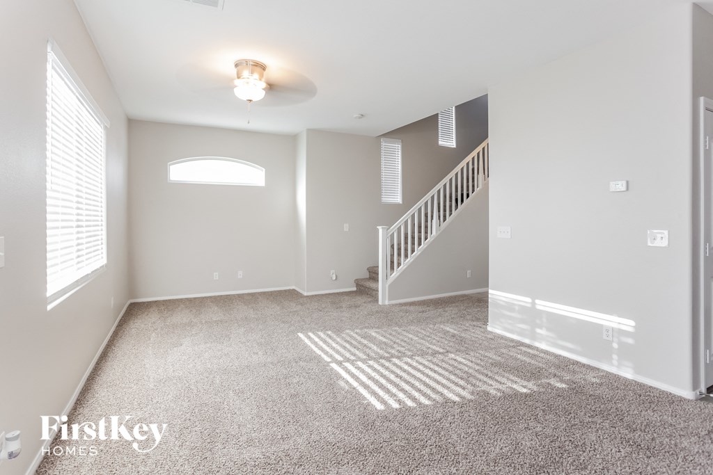 a spacious living room with carpeted floors and a staircase