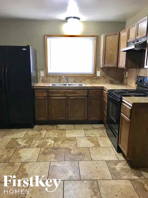 A kitchen with a black refrigerator and wooden cabinets.