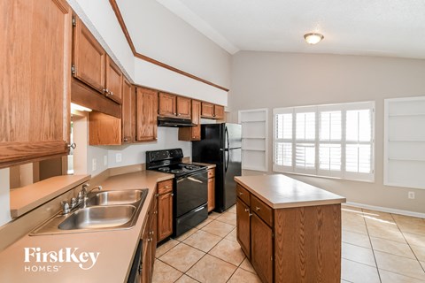 full kitchen with black appliances and wood cabinets and tiled flooring