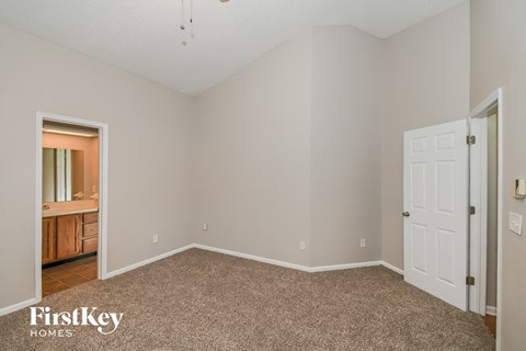 a bedroom with carpet and a door to the bathroom