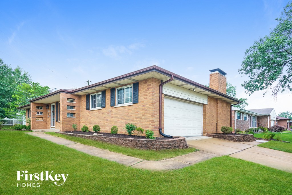 A brick house with a white garage door and a chimney.