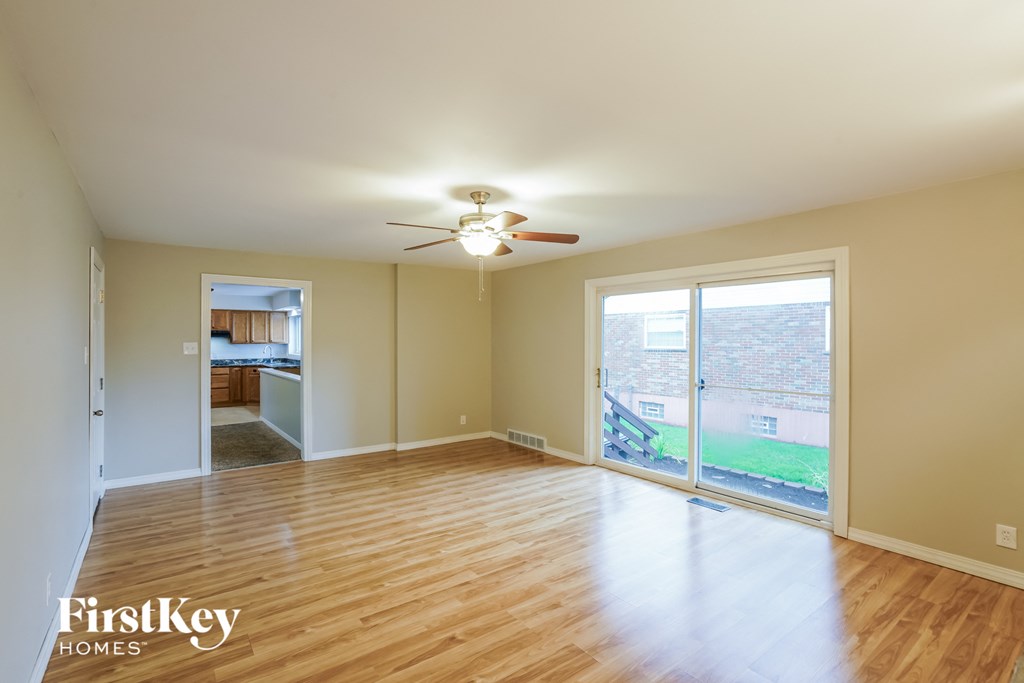 A spacious room with wooden floors and a ceiling fan.