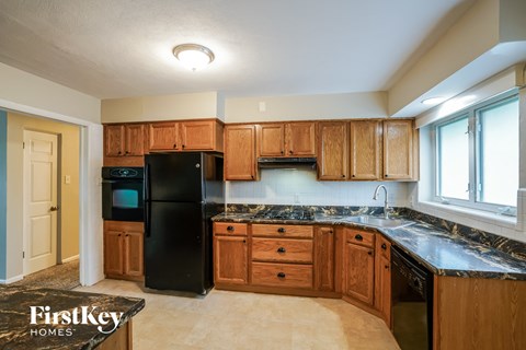 A kitchen with wooden cabinets and a black refrigerator.
