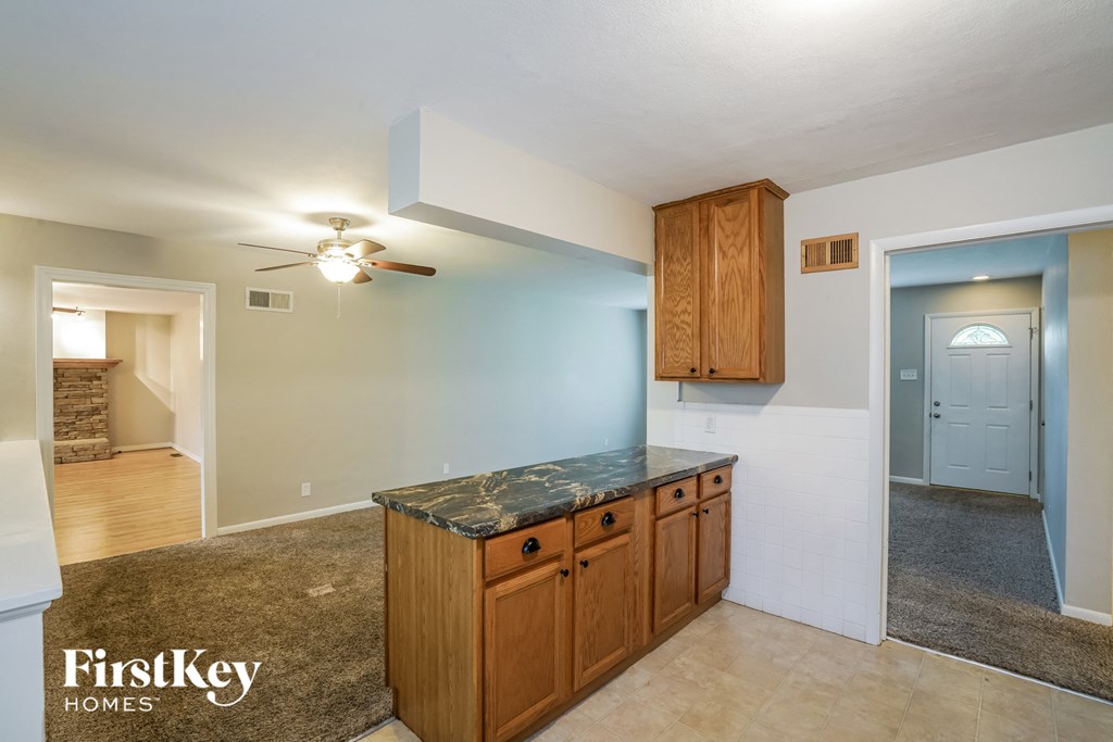 A kitchen area with wooden cabinets and a marble countertop.