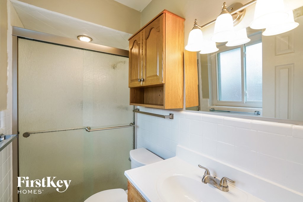 A bathroom with a white sink and a shower with a glass door.