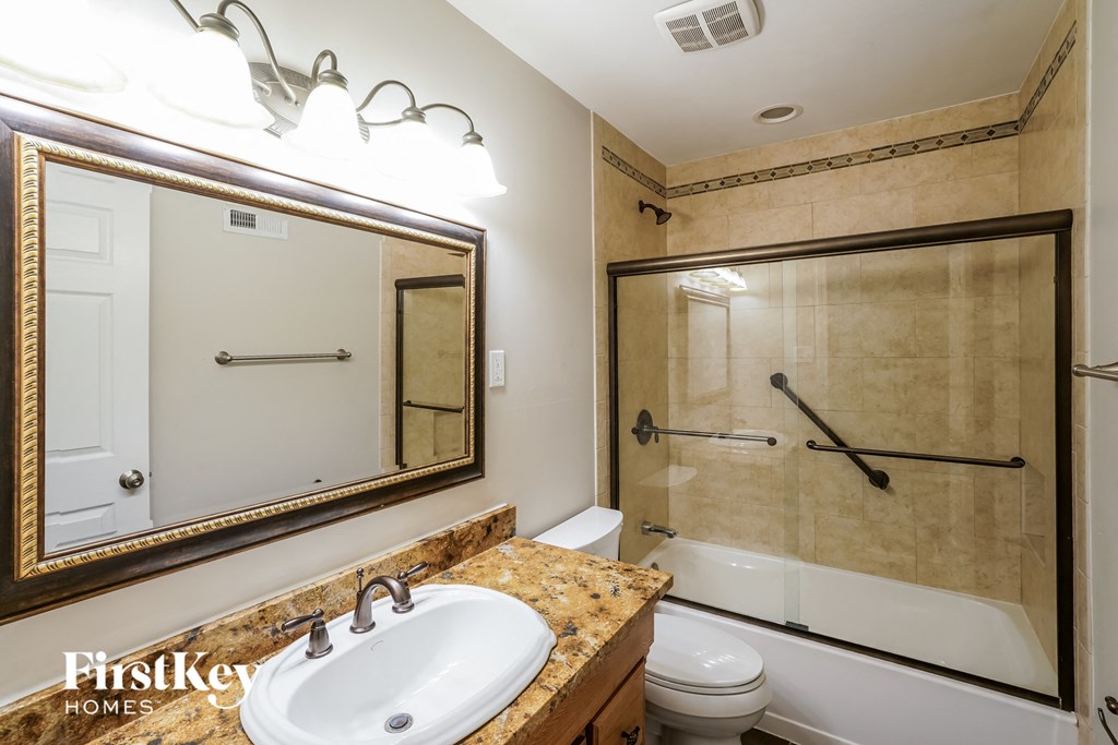 A bathroom with a sink, mirror, and shower.