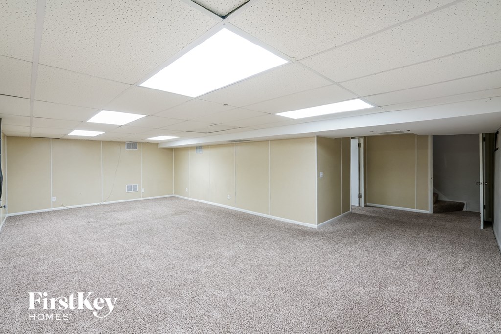 A spacious room with a carpeted floor and white walls, with a skylight above.