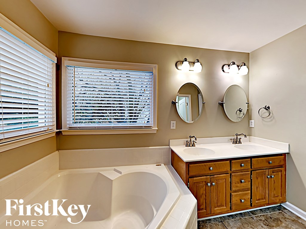 a bathroom with a tub and a sink and two mirrors