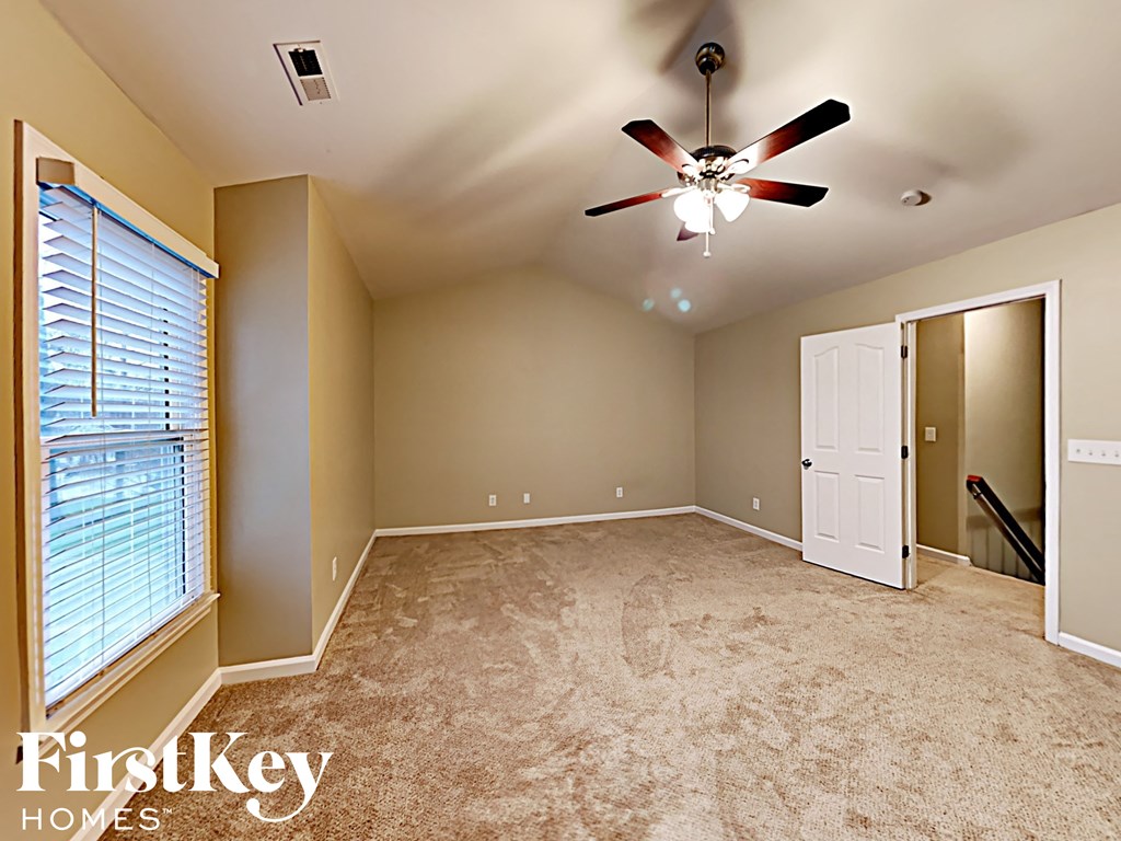 the master bedroom has a carpeted floor and a ceiling fan