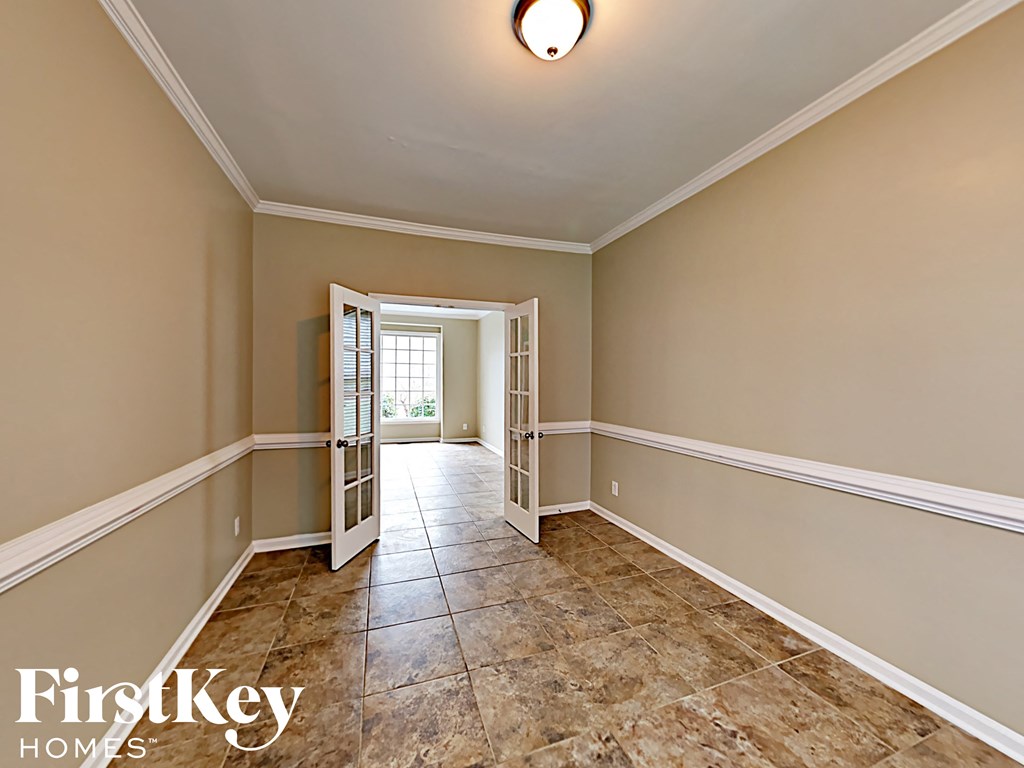 an empty living room with tiled floors and an open door to a hallway