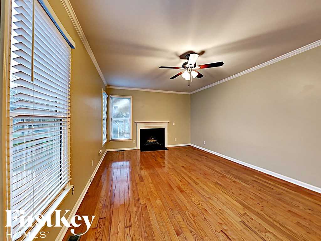 an empty living room with wood floors and a ceiling fan