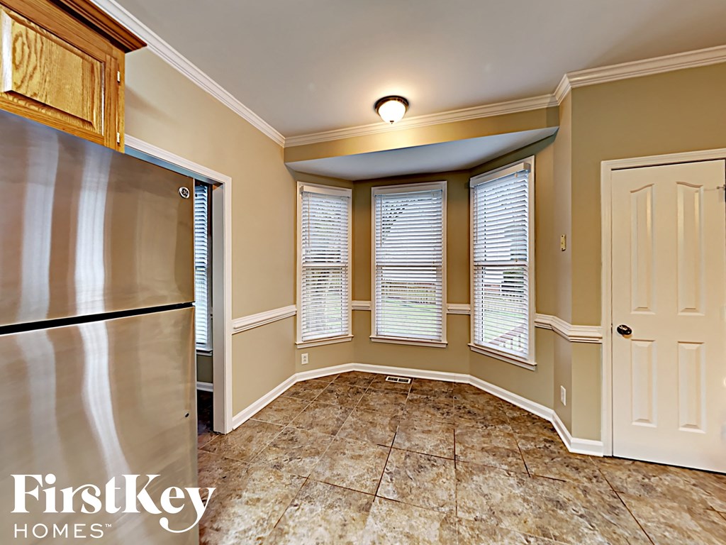 an empty kitchen with a stainless steel refrigerator and three windows