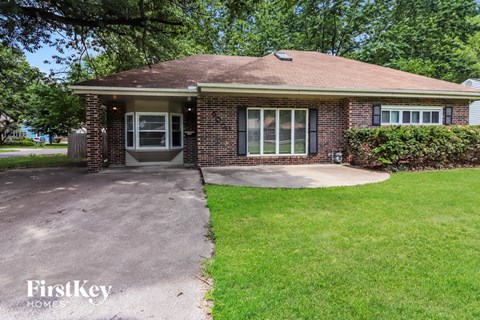 a small brick house with a driveway and grass