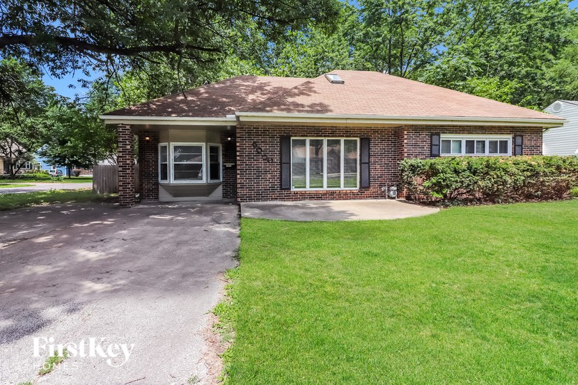 a small brick house with a driveway and grass