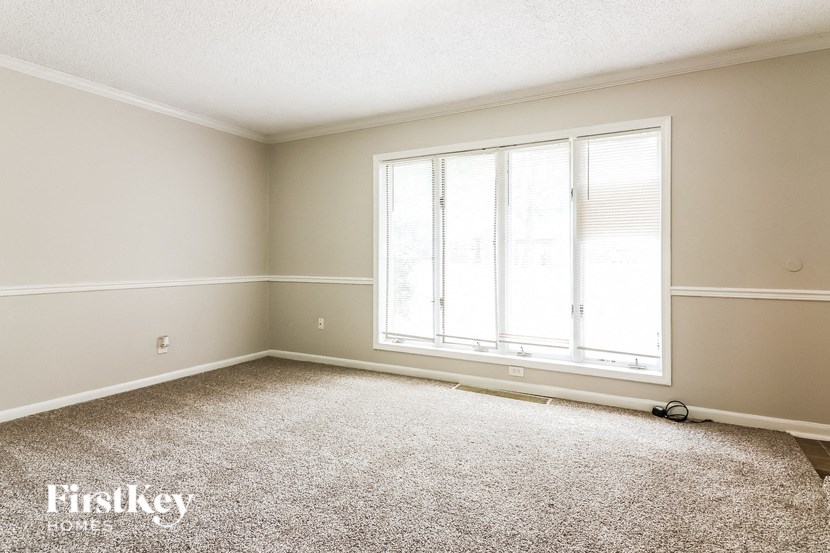 a bedroom with a large window and a carpeted floor