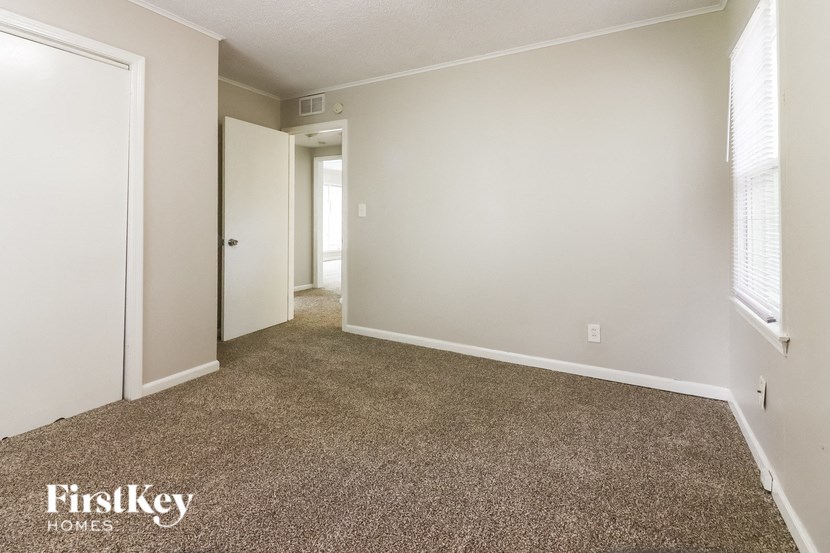 a bedroom with a carpeted floor and a door to a hallway