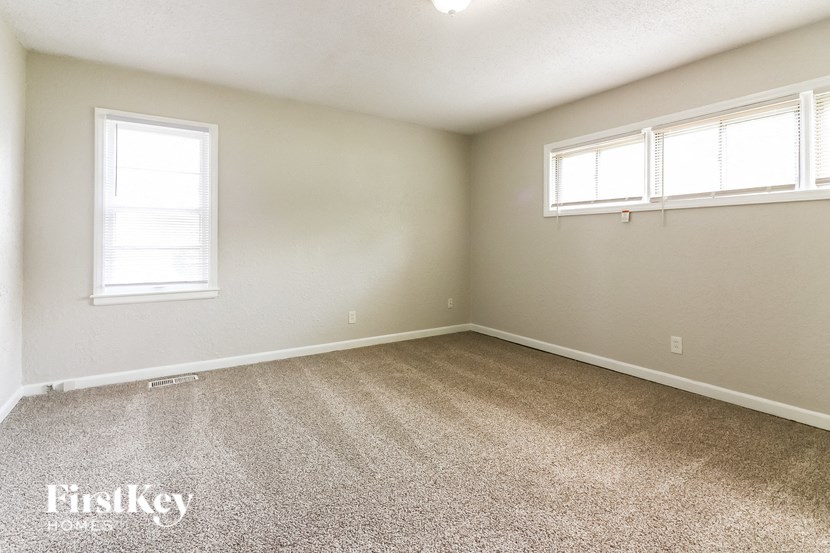 a bedroom with two windows and a carpeted floor