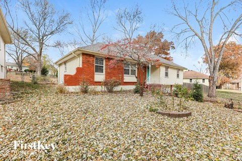 a red brick house with a yard covered in fallen leaves