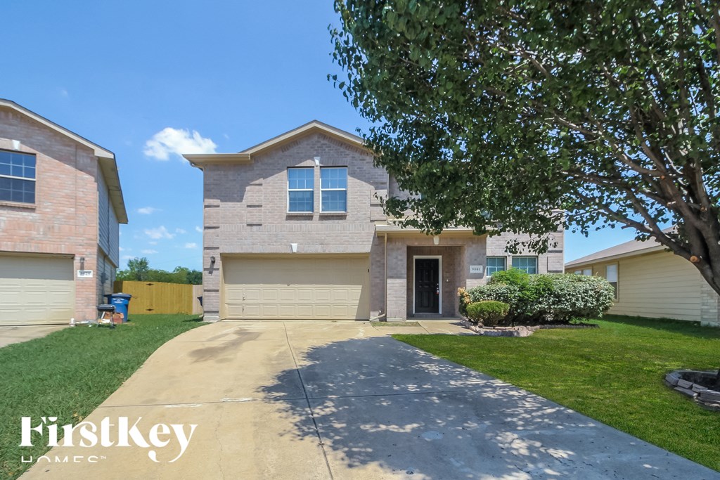 a house with a driveway and a tree in front of it
