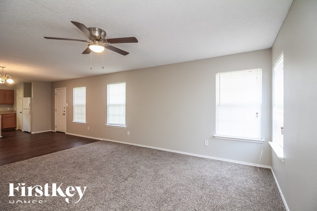 an empty living room with a ceiling fan and a window