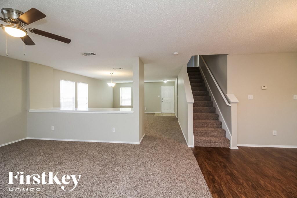 a living room with a staircase and a ceiling fan