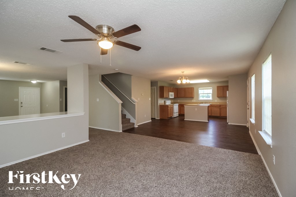 an empty living room and kitchen with a ceiling fan