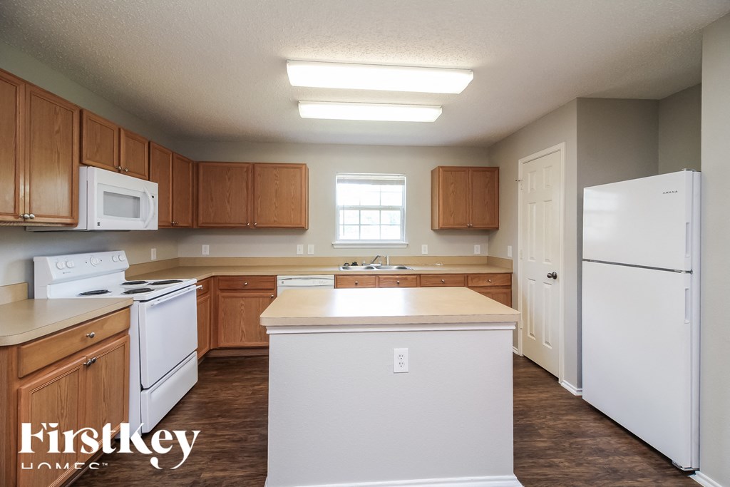 an empty kitchen with white appliances and wooden cabinets