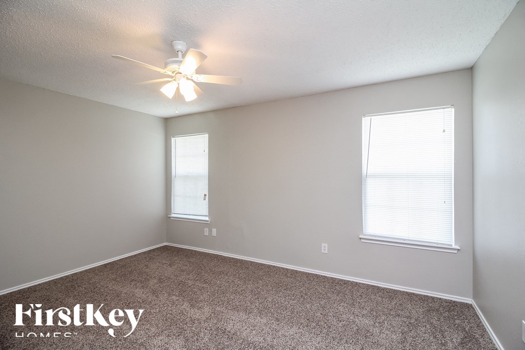 a bedroom with carpet and a ceiling fan and two windows