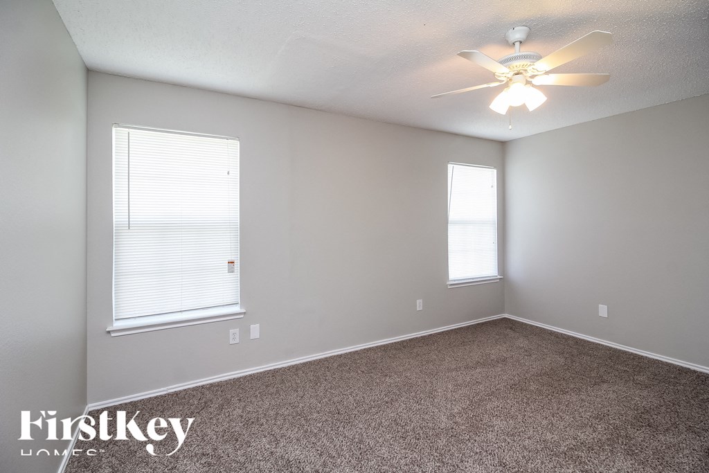 a bedroom with a ceiling fan and two windows