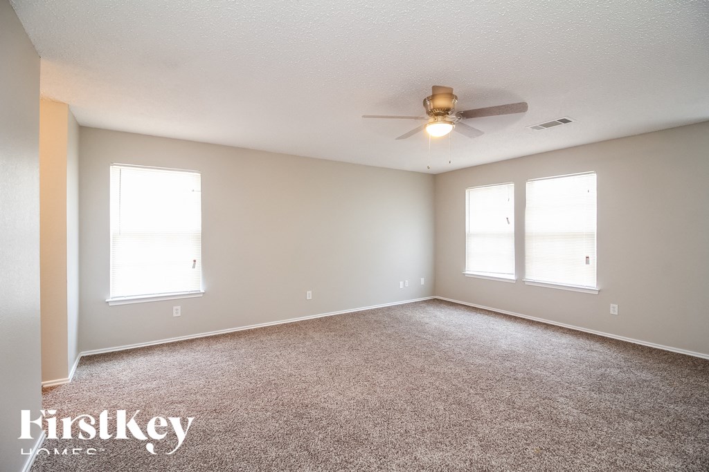 an empty living room with a ceiling fan and two windows
