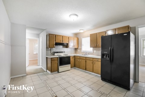 A kitchen with a black fridge and wooden cabinets.