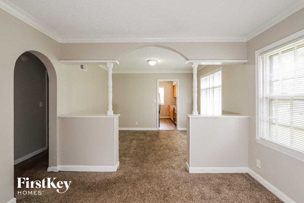 a living room with an arched doorway and a carpeted floor