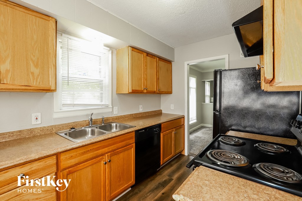 a kitchen with wood cabinets and black appliances and a sink