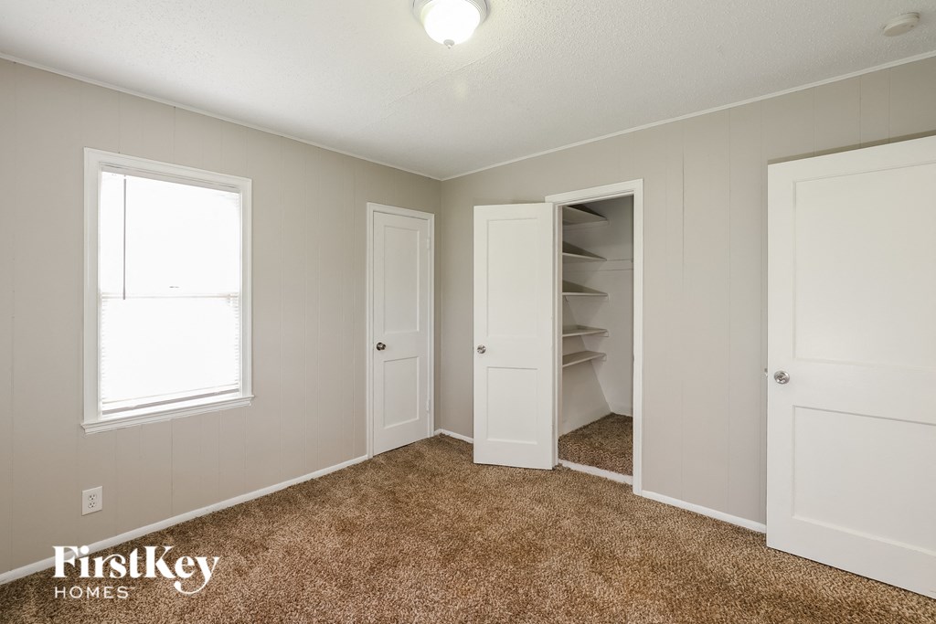a bedroom with a closet and a window and a carpeted floor