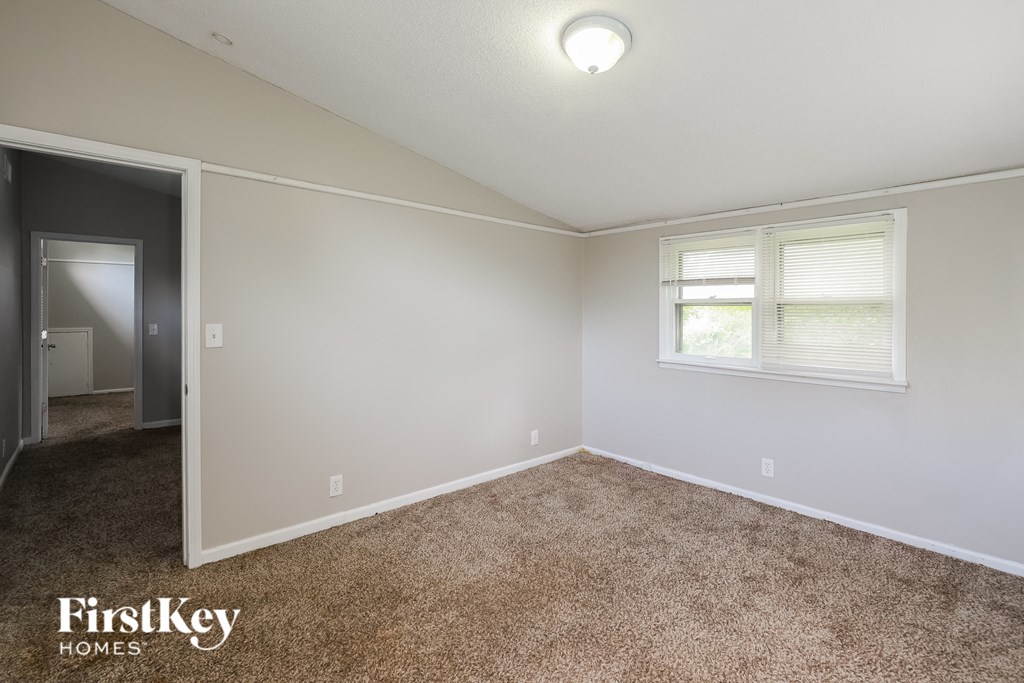a bedroom with carpet and white walls and a window