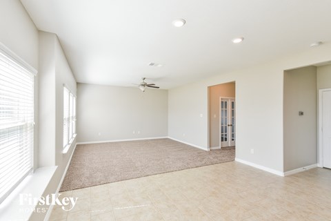 an empty living room with a ceiling fan and a window