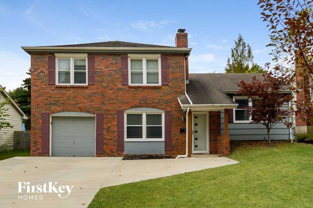 a brick house with two garage doors and a sidewalk