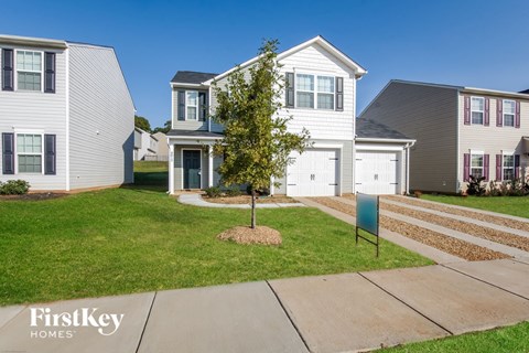 two story home with white siding and a blue sign in the front yard